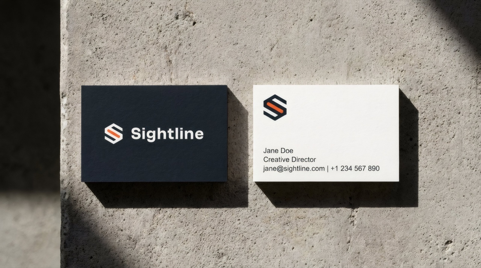 Two Sightline business cards on concrete — a graphite card with the lockup and a white card with contact details
